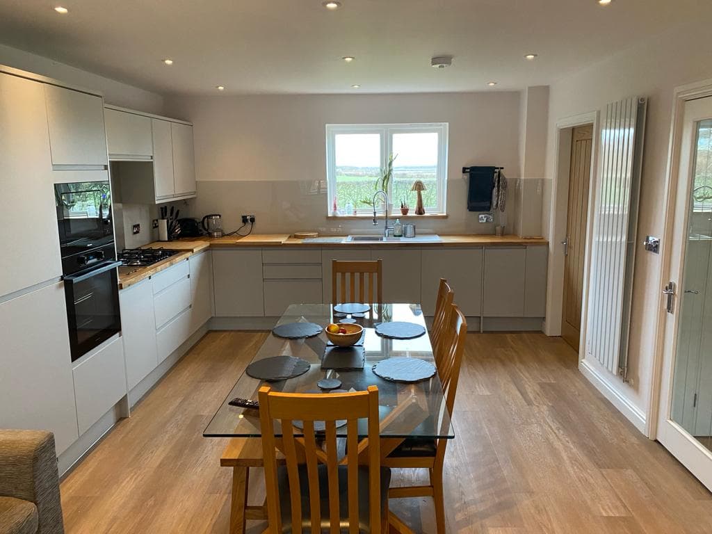 Open-plan kitchen and dining room with handleless units, oak worktops and a tall column radiator