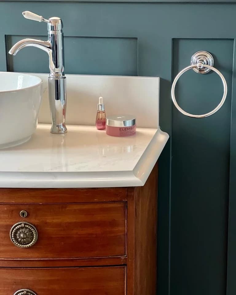 Close-up of a chrome lever tap, white worktop and timber drawers against panelled walls
