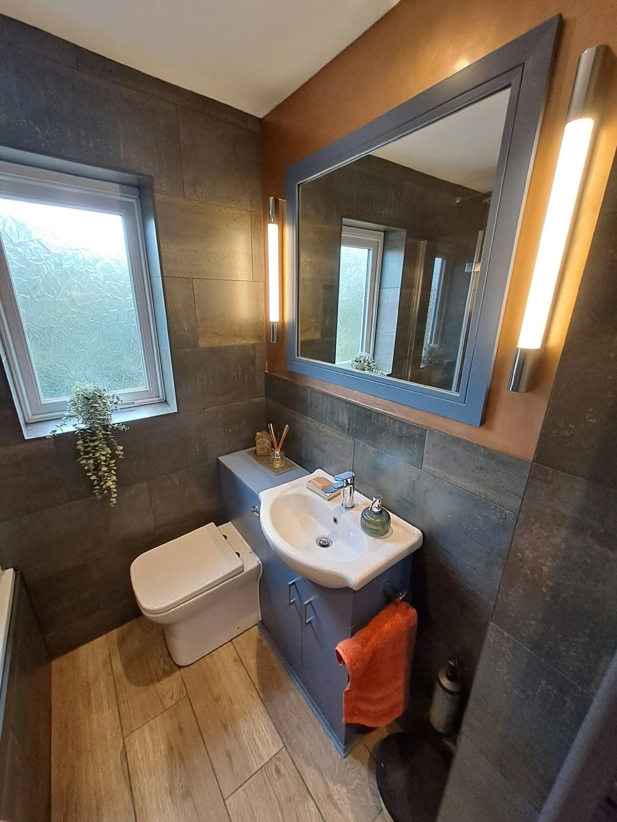Bathroom with a grey vanity unit and basin, back-to-wall toilet, framed mirror and tall wall lights