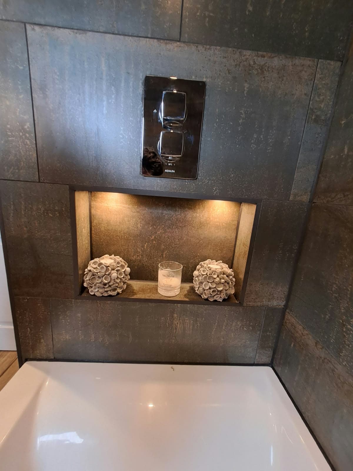 Tiled recessed niche with LED lighting below a concealed thermostatic shower valve