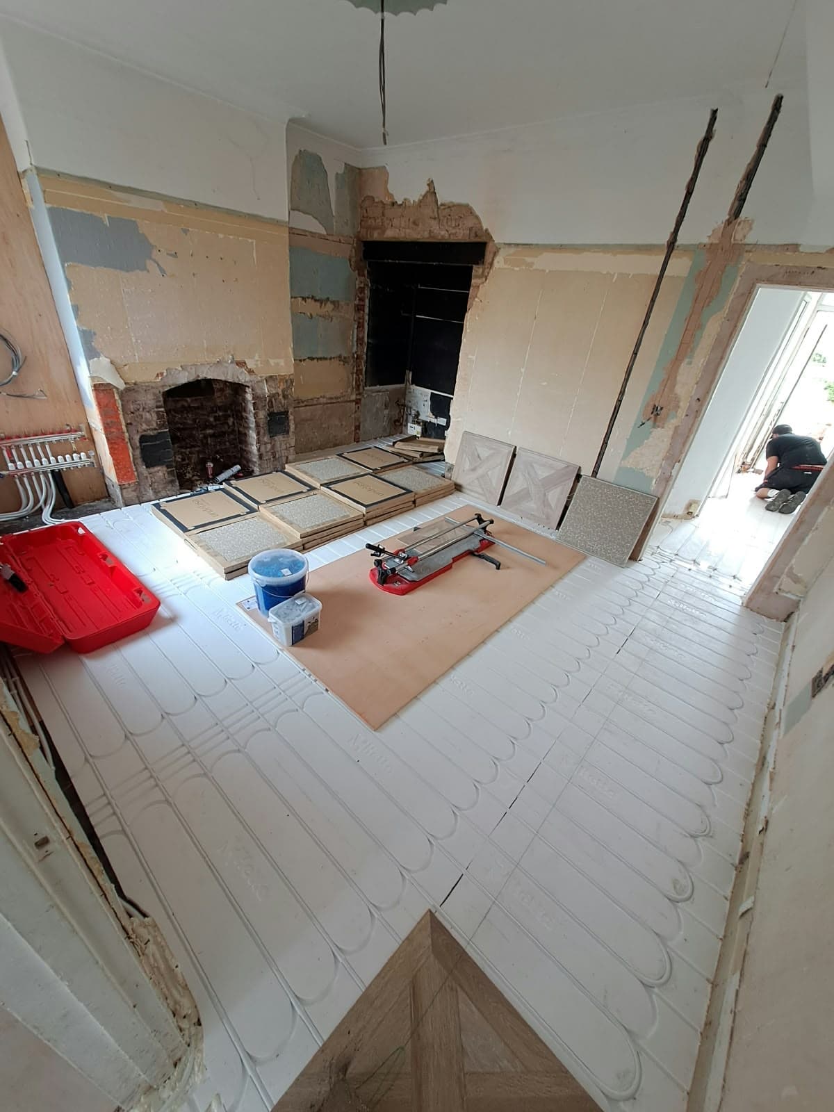 Renovation in progress with underfloor heating panels and pipework laid across the floor before tiling