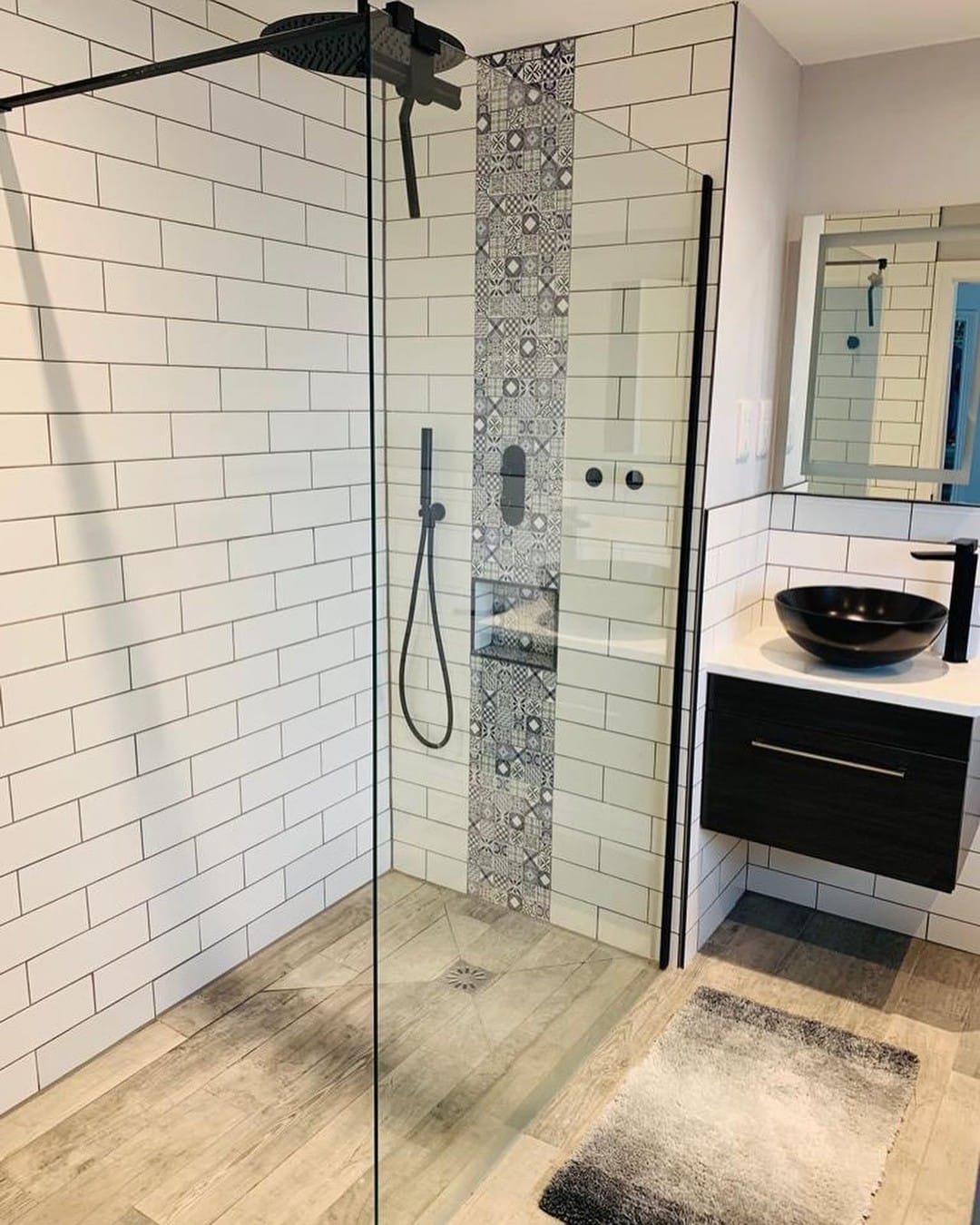 Walk-in shower with white metro tiles, a patterned feature strip, recessed niche and matt black fittings
